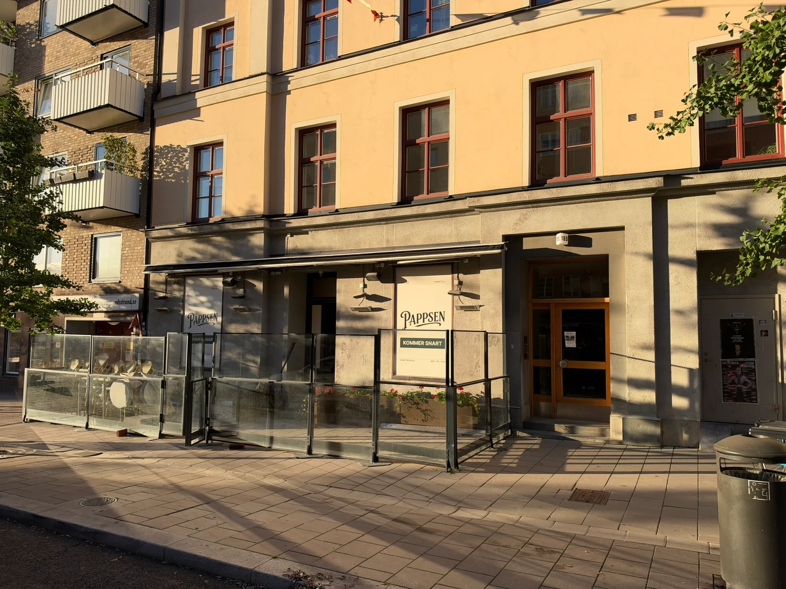Pappsens riktiga fasad i eftermiddagssol, med logotypen på de två fönsterytorna