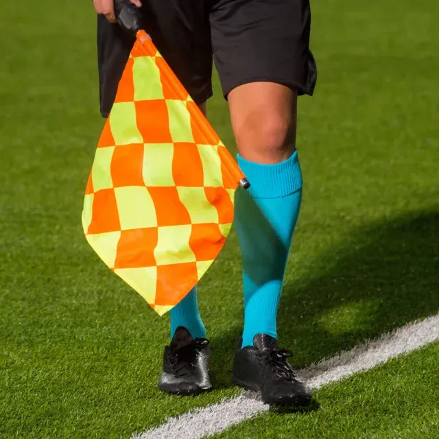 Detalj ur Reflinks källmaterial: en linjedomare med orange och gul flagga